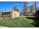 Backyard featuring a small brick building with windows and a door, green lawn, mature trees, and a clear blue sky at 3051 W 39Th Ave, Denver, CO 80211