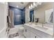 Modern bathroom featuring dual sinks, sleek white cabinets, and a shower with stylish blue accent tiles at 8939 Bellsong Cir, Littleton, CO 80125