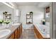 Well-lit bathroom featuring dual sinks, a soaking tub, and modern fixtures at 1545 August Ln, Brighton, CO 80601