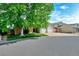 Inviting home exterior with lush landscaping, mature trees, and a wide driveway at 1545 August Ln, Brighton, CO 80601