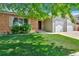 Brick and siding home with lush lawn, mature tree, and a welcoming front entrance at 1545 August Ln, Brighton, CO 80601
