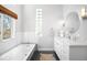 Bright bathroom featuring a soaking tub, sleek vanity, a vessel sink, and modern fixtures and finishes at 3206 S Clayton St, Denver, CO 80210