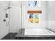 Modern bathroom featuring a tub with a subway tile surround and a walk-in shower with black pebble flooring at 3206 S Clayton St, Denver, CO 80210