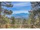 Serene backyard framed by lush trees and distant mountain views at 1692 Sand Lily Dr, Golden, CO 80401