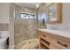 Modern bathroom with a glass enclosed shower, stone tile, and a wooden vanity at 1692 Sand Lily Dr, Golden, CO 80401