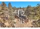 A multi-level home nestled among trees, with decks and rocky landscaping at 1692 Sand Lily Dr, Golden, CO 80401