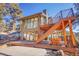 Modern home exterior with wood deck, stairs, and forested surroundings on a sunny day at 1692 Sand Lily Dr, Golden, CO 80401