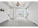 Bright living room with grey carpet, tray ceiling, modern lighting fixture, and large windows with bright outdoor views at 27196 E Alder Dr, Aurora, CO 80016