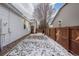 Narrow side yard with patchy snow, a wooden fence, and a small tree at 5935 E 129Th Pl, Thornton, CO 80602