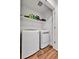 Efficient laundry room featuring a side-by-side washer and dryer set, wood-look flooring, and overhead shelving at 28304 E 6Th Pl, Watkins, CO 80137