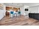 Open-concept living room features hardwood floors, a modern kitchen with a peninsula, and stylish blue bar stools at 28304 E 6Th Pl, Watkins, CO 80137