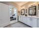 Bright bathroom with double vanity, white cabinetry, modern fixtures, and an open doorway to the bedroom at 6849 E Lowry Blvd, Denver, CO 80230
