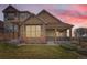 Charming townhome with stone accents, covered porch, and manicured lawn at dusk at 555 Gallegos Cir, Erie, CO 80516