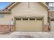 A well-maintained two-car garage with stone accents and clean curb appeal at 555 Gallegos Cir, Erie, CO 80516