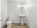 Stylish powder room featuring a pedestal sink, oval mirror, and wood-look flooring at 2887 E 103Rd Dr, Thornton, CO 80229