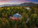 Aerial view of the home surrounded by lush forestry and mountains, and features a large deck at 11163 Conifer Mountain Rd, Conifer, CO 80433