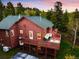 Stunning two-story home with a spacious wooden deck and outdoor seating amidst a lush green forest at 11163 Conifer Mountain Rd, Conifer, CO 80433