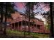 Stunning multi-level home with wood siding and multiple decks, surrounded by lush trees and vibrant sunset colors at 11163 Conifer Mountain Rd, Conifer, CO 80433