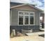 Close up of a two-story home with gray siding, large windows, light brown trim, and concrete base at 716 Belay St, Erie, CO 80516