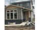 Two-story home with gray siding and light brown trim, large front-facing windows, and a covered porch at 716 Belay St, Erie, CO 80516