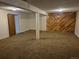 Unfinished basement space with carpeted floors and wooden accent wall ready to be updated at 2750 S Rifle St, Aurora, CO 80013
