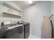 Functional laundry room with washer, dryer, floating shelves, and ironing board at 6065 Clover Ridge Cir, Castle Rock, CO 80104