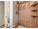 Modern shower with brown tile surround and a convenient corner shelving unit at 2488 S Victor St # E, Aurora, CO 80014