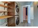 A laundry area features a stacked washer and dryer, along with built-in shelving for storage at 8555 Fairmount Dr # C202, Denver, CO 80247