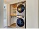 A laundry area features a stacked washer and dryer, along with built-in shelving for storage at 8555 Fairmount Dr # C202, Denver, CO 80247