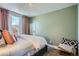 Bright bedroom with a patterned carpet, a neutral colored bed, and light pink curtains over the large window at 3249 N Clay St, Denver, CO 80211