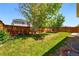 Spacious backyard featuring a lush green lawn, complemented by a wooden fence, and mature tree at 25077 E Canal Pl, Aurora, CO 80018