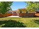 A well-maintained backyard features a grass lawn, a concrete patio, and partial brick exterior at 25077 E Canal Pl, Aurora, CO 80018