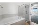 Bright bathroom features a tiled tub and shower with glass enclosure, alongside a window for natural light at 25077 E Canal Pl, Aurora, CO 80018