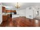 Open-concept living space with hardwood floors flowing into a kitchen with a breakfast bar and dark appliances at 25077 E Canal Pl, Aurora, CO 80018