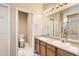 Bright bathroom featuring double sinks, a large mirror, and a separate toilet room at 5037 Pelican St, Brighton, CO 80601