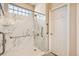 Walk-in shower featuring marble-style tile, grab bars, and a built-in seat for accessibility at 5037 Pelican St, Brighton, CO 80601
