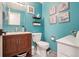 Stylish teal bathroom with a modern vanity, a white toilet, and unique wall art at 6462 E Bates Ave, Denver, CO 80222