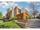 Brick townhome showcases landscaped front yard with stairs leading to the entrance on a partly cloudy day at 6462 E Bates Ave, Denver, CO 80222