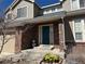 Close-up of a home's front entrance with a teal door, brick facade, and blossoming yellow flowers at 5520 Morgan Way, Frederick, CO 80504