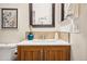 Updated bathroom featuring a wood vanity, white countertop, framed mirror, floral artwork, and a toilet at 1825 Kendall St # 107, Lakewood, CO 80214