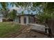 Backyard featuring mature trees, lawn, garden beds, gravel area, and home with glass enclosure at 7042 W 76Th Ave, Arvada, CO 80003