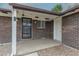 Close up on home entrance showing an iron security door and a covered porch with brick columns at 7042 W 76Th Ave, Arvada, CO 80003
