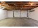 Spacious garage with exposed ceiling beams, concrete floor, and large metal garage door at 7042 W 76Th Ave, Arvada, CO 80003