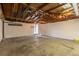 Large garage features unfinished ceiling, white walls, and concrete floor with an open door at 7042 W 76Th Ave, Arvada, CO 80003