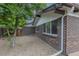 Side yard of brick home, with gravel, mature landscaping, and privacy fence at 7042 W 76Th Ave, Arvada, CO 80003
