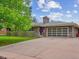Ranch style home featuring a driveway, brick exterior, a garage door and mature trees at 423 Empire St, Aurora, CO 80010