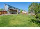 Lush green backyard with a wooden fence, shade trees, and a raised deck with stairs, perfect for outdoor living at 430 Chestnut Way, Broomfield, CO 80020