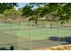 Outdoor tennis court with chainlink fence, green surface, visible net, and shady trees in the background at 430 Chestnut Way, Broomfield, CO 80020