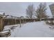 Snowy backyard with wooden fence, mature trees, and garden at 646 N 13Th Ave, Brighton, CO 80601