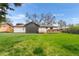 Green backyard lawn features a deck and mature trees with a partial view of the home's exterior at 13416 W 22Nd Pl, Golden, CO 80401
